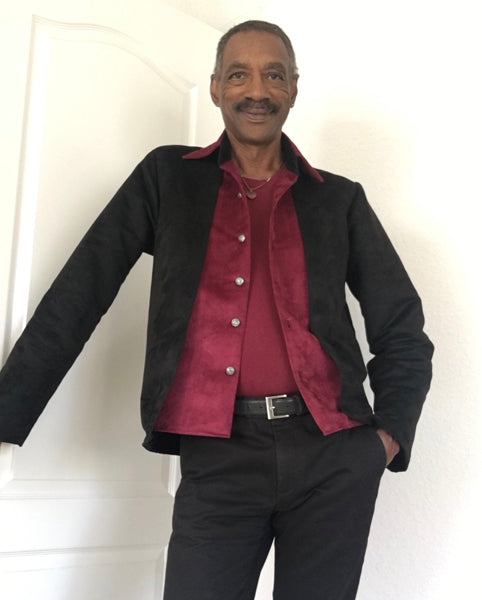 Man wearing a black jacket with red lining and a red shirt against a white background