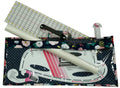 Set of sewing tools including a ruler, cutting mat, and pattern guide on a white background