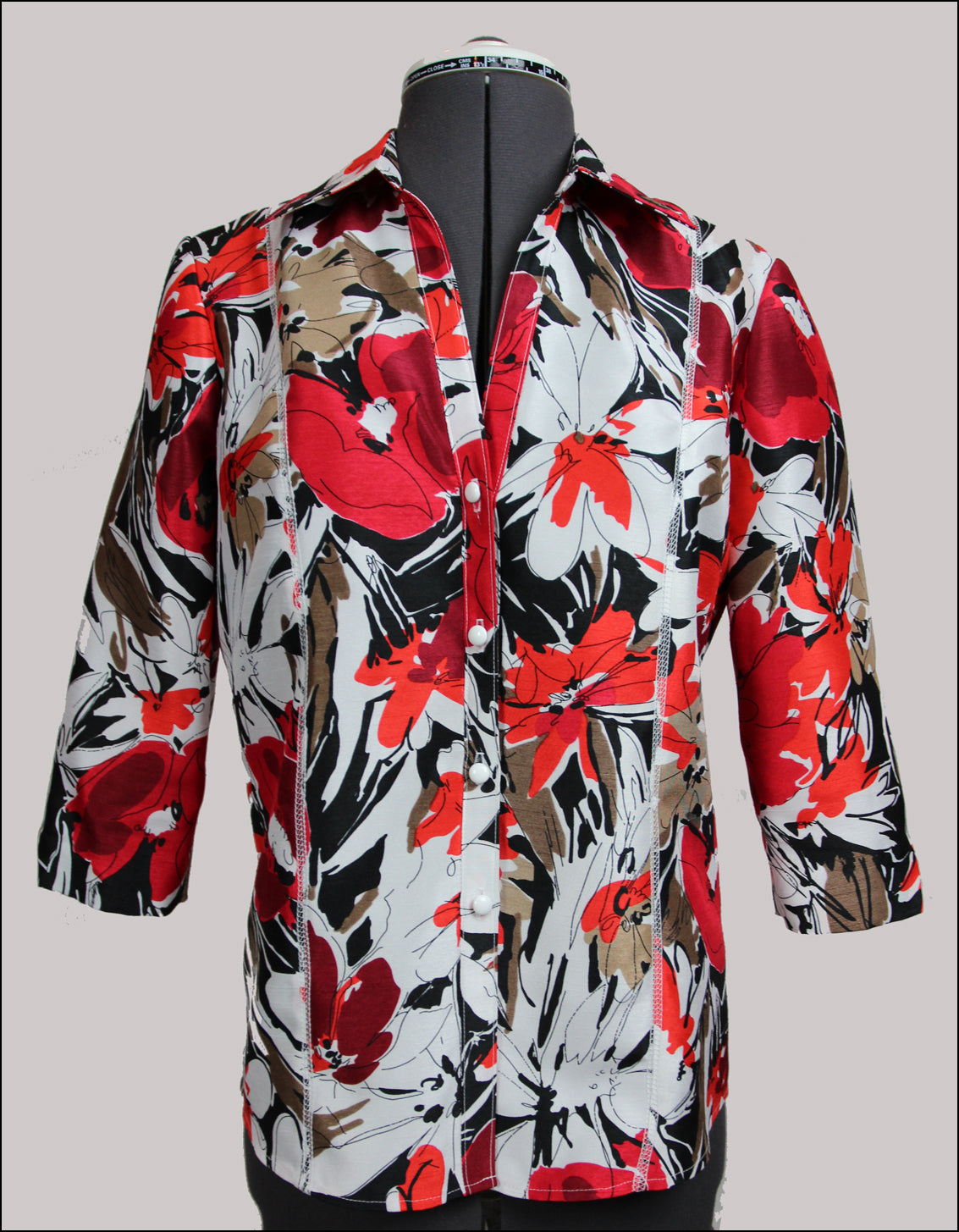 Colorful floral-patterned shirt on a mannequin against a gray background