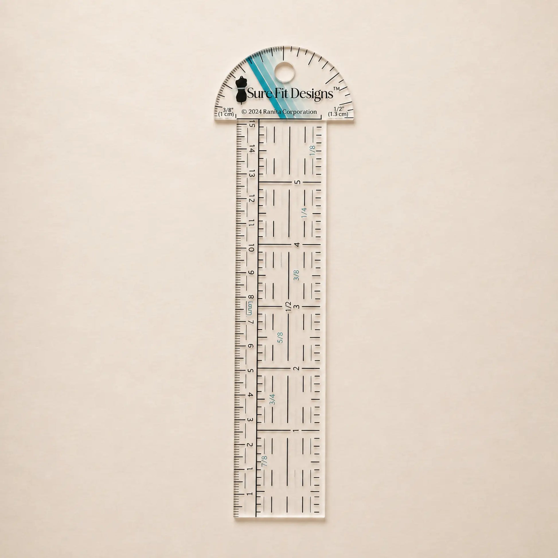 A clear acrylic ruler and protractor set by Sure Fit Designs, featuring black measurement markings and a blue accent stripe on the protractor cap, displayed on a light beige textured background.