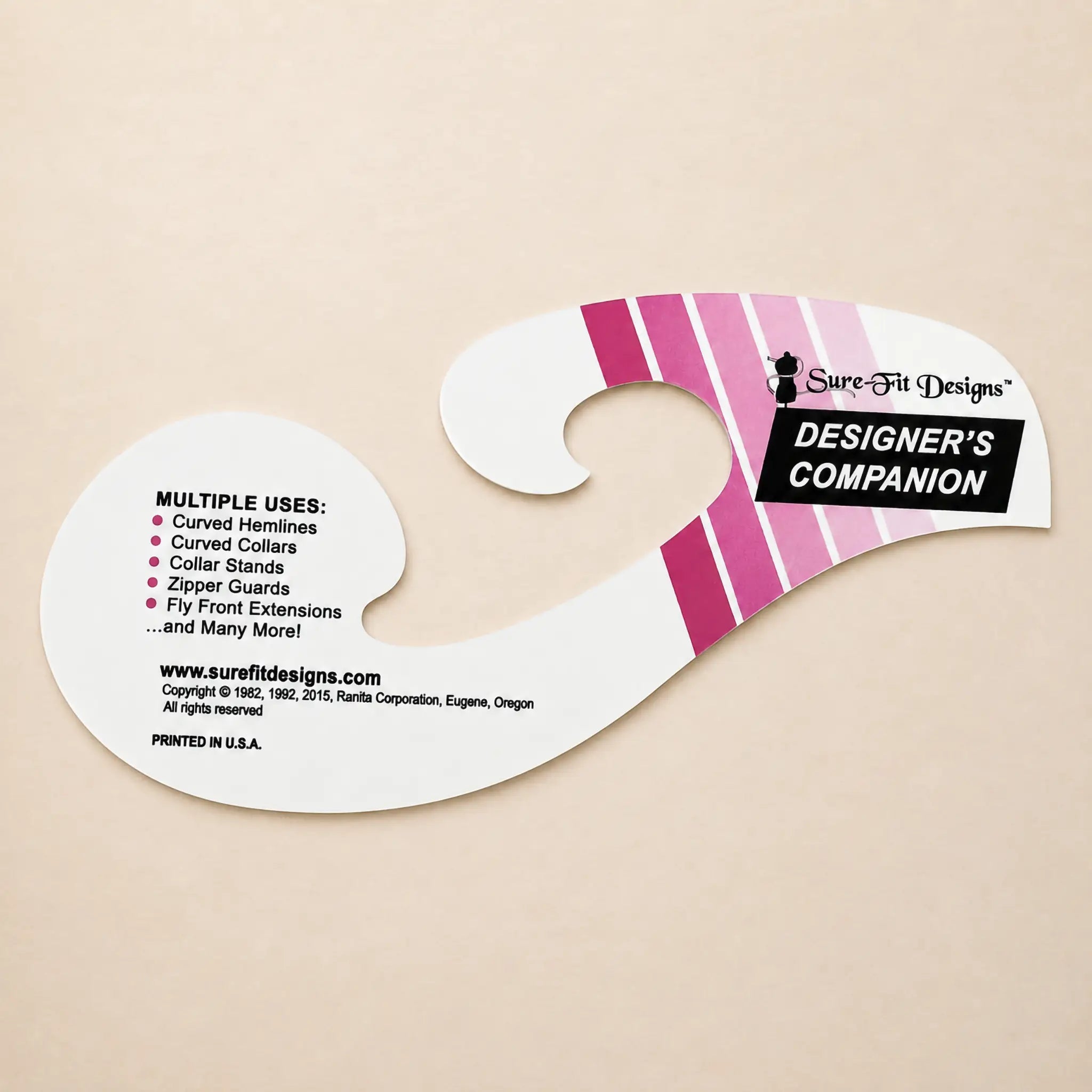 A Sure-Fit Designs Designer's Companion curved cardboard hanger insert on a light beige background, featuring pink and white diagonal stripes and black text.