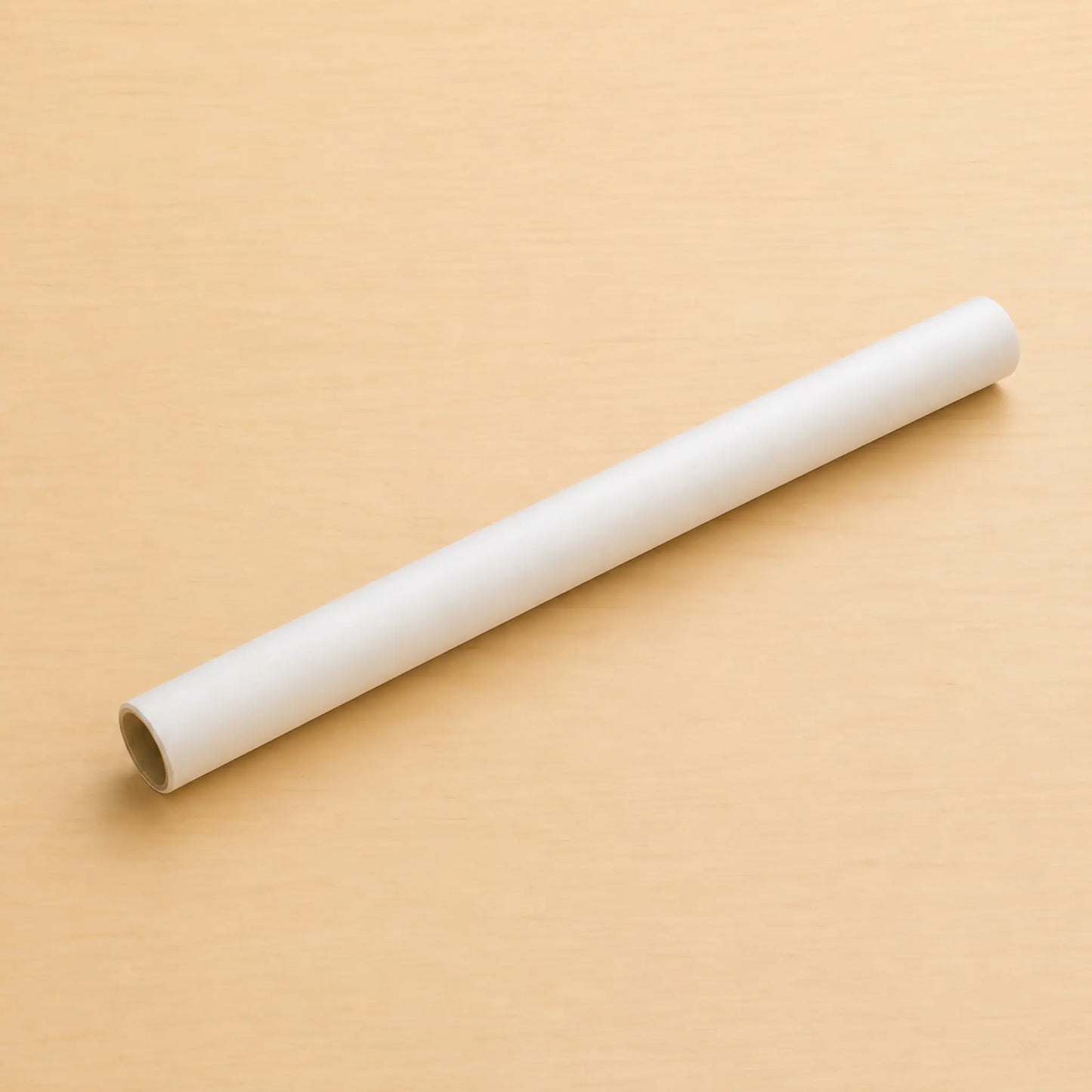 A plain white cylindrical rod or tube lying diagonally on a light beige wood-textured background.