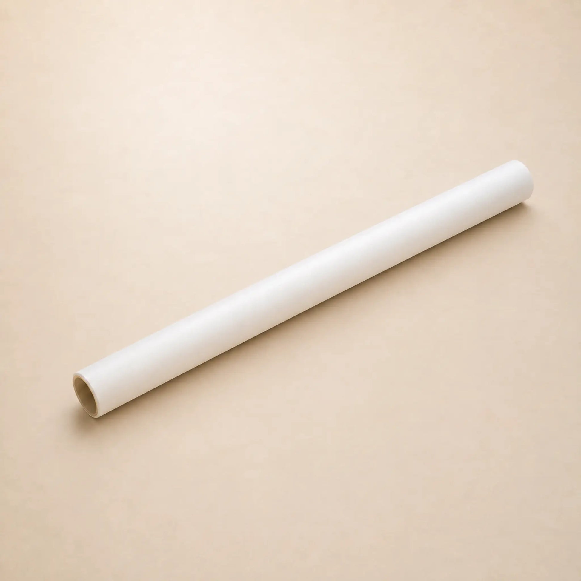 One roll of transparent vellum lying diagonally on a plain beige background.