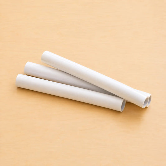Three white plastic cylindrical sleeves or guides arranged diagonally on a light beige wooden surface.