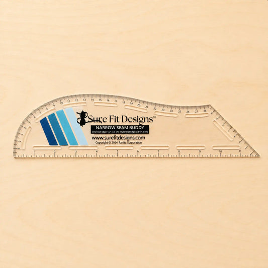 A clear plastic measuring ruler with printed measurement markings and a central Sure Fit Designs label, placed on a light wood background.