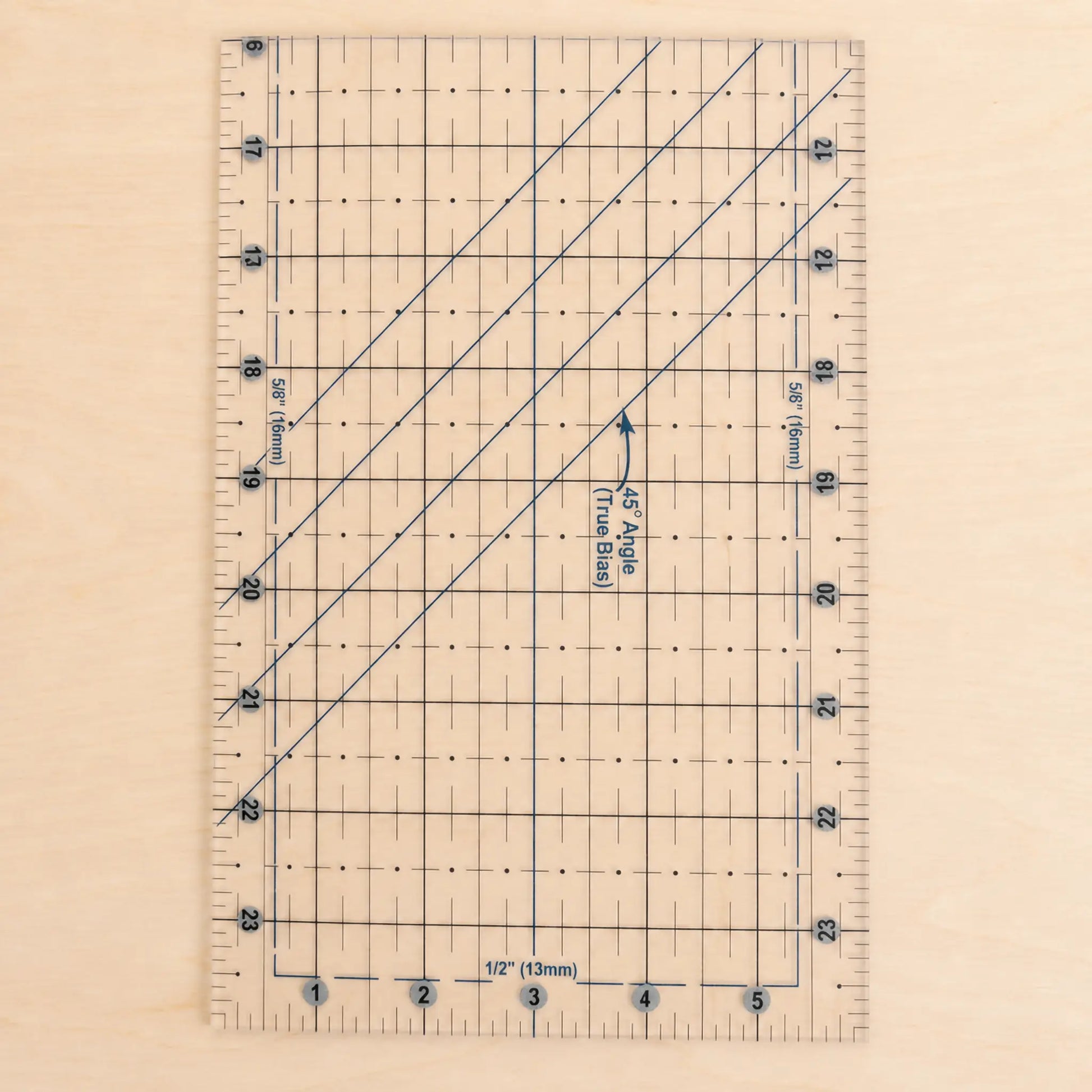 A clear acrylic quilting ruler with blue grid lines, measurement markings, and diagonal conversion guides, shown on a light wood background.