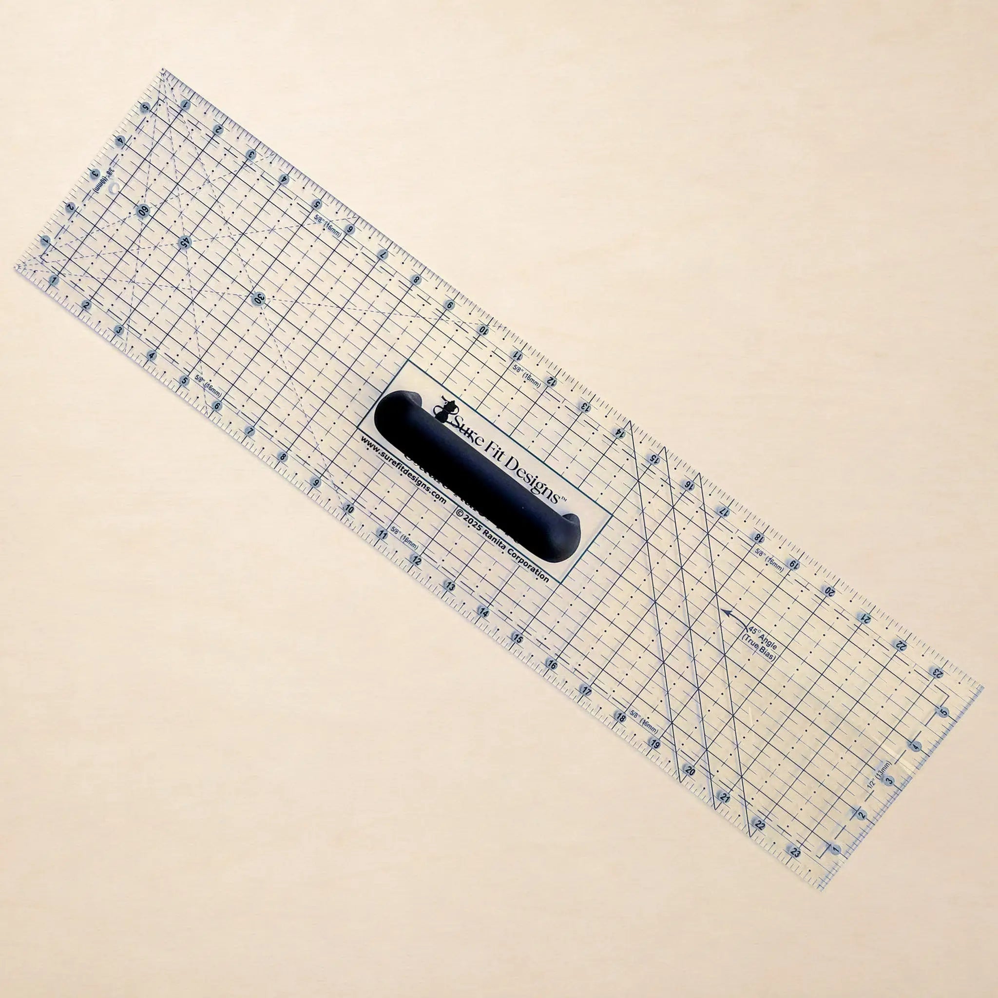 A clear acrylic rotary cutter with blue grid lines and a black handle, shown diagonally on a light beige background. The brand 'Made In Design' is printed on the handle.