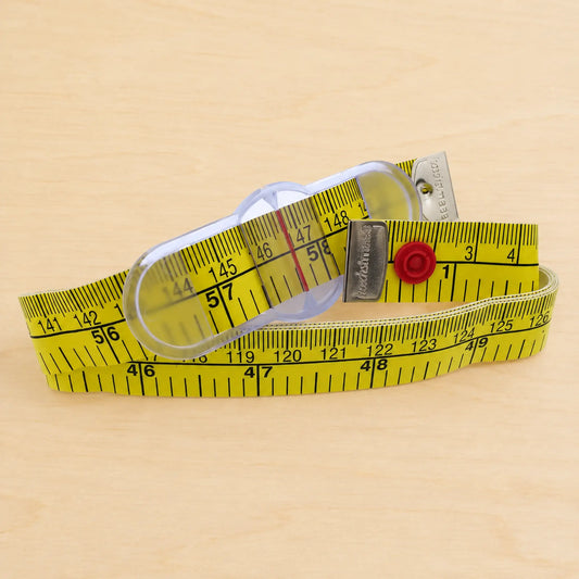 A yellow tape measure with black printed measurement markings and a red release button, photographed on a light wood surface.