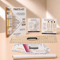 A sewing pattern kit and fitting tools arranged on a warm beige studio surface. Visible items include a 'PANTS KIT' instruction booklet, two Sure Fit Designs course cards, a clear acrylic ruler, a black sewing machine foot, a curved measuring template, and a white fabric roll.